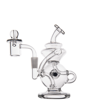 The MJ Arsenal Mini Jig Mini Dab Rig is a clear glass water pipe with a rounded base, curved neck, side handle, built-in storage jar, and left-side bowl, beautifully photographed on a white background.