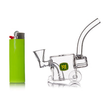 A green lighter stands upright beside the MJ Arsenal Woodchipper Blunt Bubbler, a small clear glass bubbler with a curved mouthpiece and yellow logo, both displayed on a white background for easy water filtration.