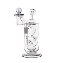 The MJ Arsenal Titan Mini Dab Rig is a clear borosilicate glass piece with intricate, interconnected chambers and a removable top, designed for filtration and smoking. The product is photographed against a plain white background.