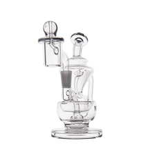 The MJ Arsenal Claude Mini Dab Rig is a clear glass piece with a cylindrical base, bent neck, attached banger, and smooth rounded details, shown against a plain white background.