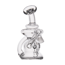 The MJ Arsenal Hydra Vape Edition is a clear glass water pipe with an abstract, curved design that functions as both a splash-resistant bubbler and a mini dab rig, shown against a plain white background.
