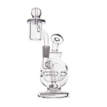The MJ Arsenal Royale Mini Dab Rig is a clear borosilicate glass rig with a round base, bent neck, attached quartz banger, and carb cap, shown standing upright on a white background.