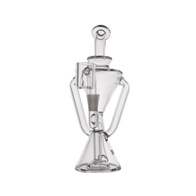 The MJ Arsenal Time Turner Mini Dab Rig is a clear borosilicate glass rig featuring a conical base, angled side handles, and a cylindrical mouthpiece at the top, designed for smoking.