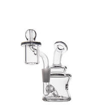 The MJ Arsenal Jammer Mini Dab Rig is a compact borosilicate glass piece with a cylindrical chamber, curved neck, quartz banger, and carb cap for vaporizing concentrates, shown against a white background.