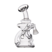 The MJ Arsenal Hydra Vape Edition is a clear glass mini dab rig with an intricate curved design, a tilted mouthpiece, and a joint for bowls or vape pen adapters, showcased on a plain white background.