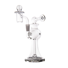 The MJ Arsenal Apollo Mini Dab Rig is a clear borosilicate glass piece with a flared base, curved neck, and built-in bowl and cap for smoking or vaporizing, designed to preserve flavor. Shown on a plain white background.