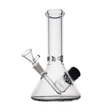 The MJ Arsenal Cache Bong features clear borosilicate glass in a beaker shape with a straight neck, angled downstem, and removable bowl. Its simple, transparent design is shown against a plain white background.