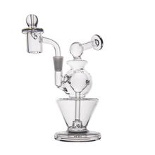 The MJ Arsenal Gemini Mini Dab Rig, made from clear borosilicate glass, features a wide base, round chamber, angled neck, and includes an attached bowl with dome-shaped carb cap—sleek and portable against a white background.