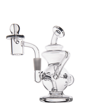 The MJ Arsenal Mini Jig Mini Dab Rig, a clear compact recycler with curved neck, quartz banger, rounded base, and built-in storage jar, is shown against a plain white background.