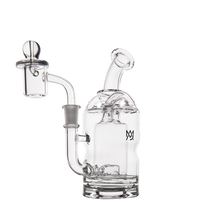 The MJ Arsenal Turbine Mini Dab Rig, made of clear borosilicate glass with a rounded chamber, angled mouthpiece, and a handled bowl, blends style and function—shown here against a plain white background.