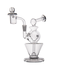 The MJ Arsenal Gemini Mini Dab Rig is a clear borosilicate glass piece with multiple chambers, a bent neck, and round base. Its intricate design makes this portable rig stand out against a plain white background.