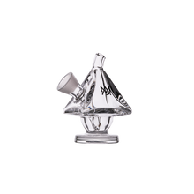 The MJ Arsenal King Bubbler is a clear borosilicate glass piece shaped like a small house or tent, featuring an angled mouthpiece, base for water filtration, and a prominent "M" logo on one side, shown against a plain white background.