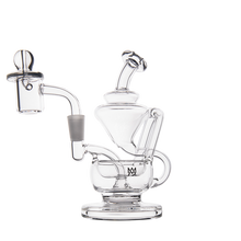 The MJ Arsenal Claude Mini Dab Rig is a transparent glass piece featuring multiple chambers, a bent mouthpiece, quartz banger, and bubble carb cap, shown against a plain white background.