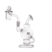The MJ Arsenal Atlas Mini Dab Rig is a clear borosilicate glass water pipe with a round base, side handle, angled neck, detachable quartz banger, and logo on the body, displayed against a white background.