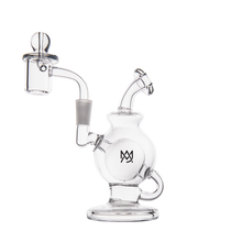 The MJ Arsenal Atlas Mini Dab Rig is a clear borosilicate glass rig with a round base, side handle, attached quartz banger, marble carb cap, and features a black logo on the chamber. Displayed on a white background.