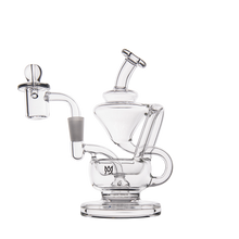 The MJ Arsenal Claude Mini Dab Rig is a clear glass recycler with intricate curved and angled chambers, a side mouthpiece, a detachable left-side bowl, and a sturdy round base. The product is photographed on a plain white background.