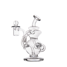 The MJ Arsenal Mini Jig Mini Dab Rig is a clear glass piece with intricate curves, a round base, a curved neck, and an attached side chamber featuring a built-in storage jar, all shown against a plain white background.