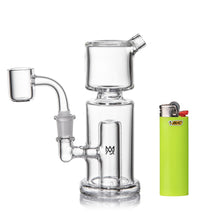 The MJ Arsenal Column Mini Dab Rig, crafted from clear borosilicate glass and featuring a 10mm quartz banger, sits next to a neon green Bic lighter for size reference. Its minimalist look is highlighted by a small front logo.