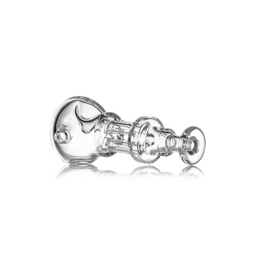The MJ Arsenal Tetra—a clear, intricately designed borosilicate glass hand pipe with multiple chambers and rounded elements—rests on its side against a white background, gently reflecting light beneath it.
