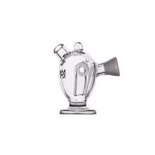 The MJ Arsenal Dubbler Original Double Bubbler is a clear borosilicate glass water pipe with a teapot shape, funnel-shaped mouthpiece, rounded body, and an overlapping M and W logo on the side for smooth filtration.