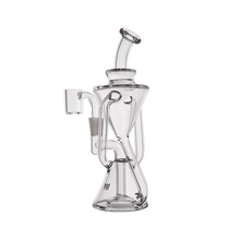 The MJ Arsenal Time Turner Mini Dab Rig is a clear borosilicate glass piece with a unique geometric design, multiple chambers and tubes, a flared mouthpiece, and a side-mounted bowl attachment.