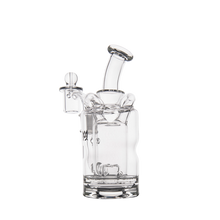 The MJ Arsenal Turbine Mini Dab Rig is a clear borosilicate glass water pipe with a cylindrical base, curved mouthpiece, and side chamber with glass stopper, inspired by the Inception Turbine Perc design. Photographed on a white background.