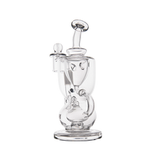 The MJ Arsenal Titan Mini Dab Rig, made of clear borosilicate glass with a curved design, wide base, side handle, and attached bowl piece, stands upright on a plain white background.