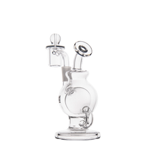 The MJ Arsenal Atlas Mini Dab Rig, made of clear borosilicate glass with circular accents and a cylindrical base, features an attached bowl with a round handle, shown against a plain white background.