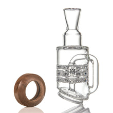 The MJ Arsenal Alpine Series - Halo Peak Top is a clear borosilicate glass smoking accessory with intricate inner chambers, shown upright next to a circular wooden ring—a premium glass upgrade for your Puffco Peak.