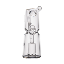The MJ Arsenal Turret Mini Dab Rig is a clear borosilicate glass rig with a cylindrical base, internal percolator, and angled mouthpiece, designed for smoking or vaporizing. It stands upright against a plain white background.