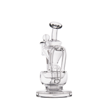 The MJ Arsenal Claude Mini Dab Rig is a clear glass recycler with intricate curves and loops, standing upright on a round base against a plain white background.