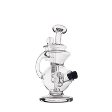 The MJ Arsenal Mini Jig Mini Dab Rig, featuring clear glass, a round base, curved neck, and attached bowl, stands upright on a plain white background.