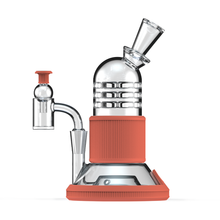 The Softglass Tandem Rig Kit is a modern water pipe made from borosilicate glass with red platinum-cured silicone accents, featuring a transparent body, bent mouthpiece, and side percolator, set against a white background.