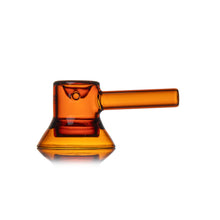 The MJ Arsenal Grotto Glass Pipe is a modern borosilicate hand pipe in translucent amber, with a cylindrical handle and wide, flat base, shown on a white background.