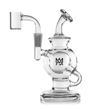 The MJ Arsenal Atlas Mini Dab Rig is a clear borosilicate glass rig with a round chamber, angled mouthpiece, sturdy base, side handle, and front “MJ” logo. It includes a quartz banger for concentrates.