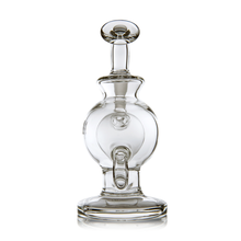 The MJ Arsenal Atlas Mini Dab Rig, crafted from clear borosilicate glass with a round body, flat base, and decorative handle-like detail, stands upright on a white background.