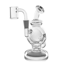 The MJ Arsenal Atlas Mini Dab Rig is a compact borosilicate glass rig with a round chamber, bent mouthpiece, side percolator tube, flat base, black crown logo on the chamber, and a bucket-style quartz banger attachment.
