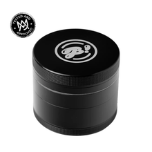 The BIGFUN! Large Grinder is a black, cylindrical aluminum grinder with a textured grip and stylized JB! logo on top. A “Tested and Approved” emblem appears in the upper left. The white background highlights its effective pollen sift design.