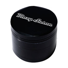 The Blazy Susan Grinder V2 is a black, round aluminum grinder featuring a spacious grind chamber and "Blazy Susan" in white stylized font on its top lid.