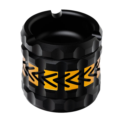 A black, cylindrical ashtray with a faceted geometric surface and yellow arrow accents. Crafted to pair perfectly with the Human Grade Grinder 8AT, it includes a cigarette notch—an essential for any grinder setup.