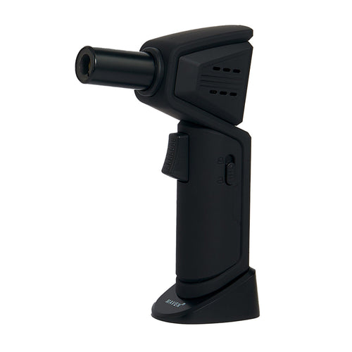 The Maven Nova Torch (Unfilled) is a black, handheld butane refillable lighter with a nozzle, ignition button, and adjustable flame, shown upright on a flat base against a white background.