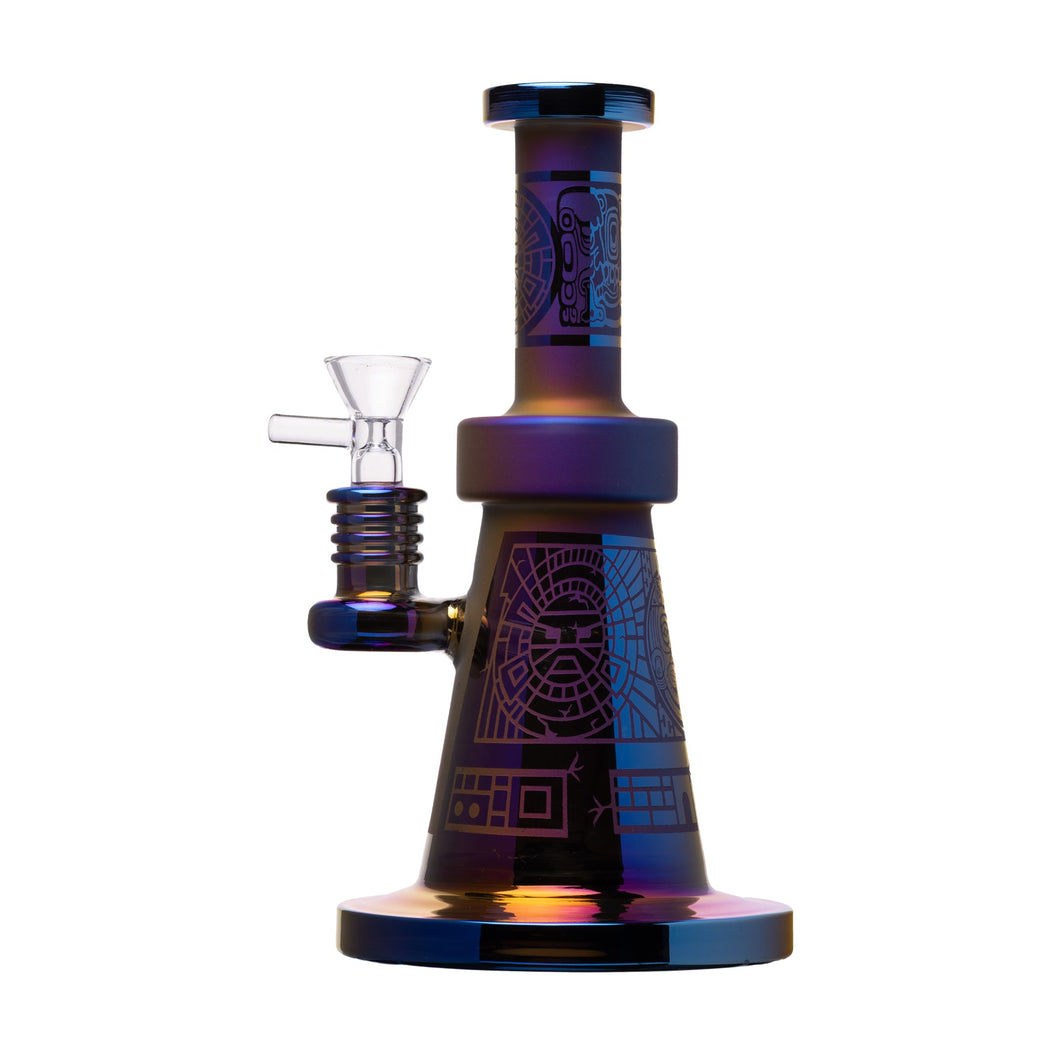 The Human Grade Aztec (Sandblasted) Glass Water Pipe is a colorful metallic borosilicate piece with geometric designs, a wide base, cylindrical neck, and a clear glass bowl attached to the side.