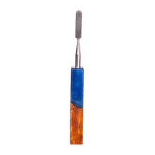 The MJ Arsenal Stabwood Dab Tool features a stainless steel rectangular blade and a blue-amber epoxy resin handle with a wood-like pattern, perfect for MJ Arsenal fans. Shown isolated on a white background.