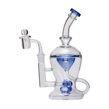 The Human Grade The Nuke Glass Rig is a clear borosilicate glass dab rig with blue accents, a curved neck, wide base, side attachment, and mushroom cloud perc spheres inside.