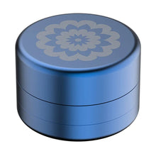 The Flower Mill 2" Next Gen Standard Grinder is a compact, round, metallic blue aluminum grinder with a silver mandala-style floral pattern on the lid, shown against a white background.
