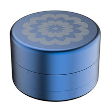 The Flower Mill 2.5" Next Gen Standard Grinder is a round, metallic blue aircraft-grade aluminum container with a silver floral mandala pattern on the lid, displayed against a white background.