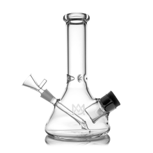 The MJ Arsenal Cache Bong is a clear borosilicate glass beaker with a wide base, straight neck, angled downstem, removable bowl, black-rimmed carb cap, and features a subtle logo on the front.