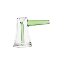 The MJ Arsenal Vulkan Bubbler is a portable borosilicate glass bubbler with a clear wide base, green handle, and a vertical green glass tube inside, combining style and functionality. Photographed on a white background.
