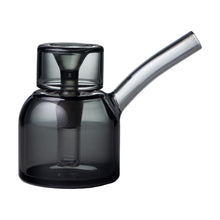 The NWTN Home Vesper Bubbler is a borosilicate glass teapot with a cylindrical body, wide lid, long curved spout, and a gray tint for a modern minimalist look.