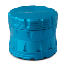 The Human Grade Grinder 2A (2.5" 4-Piece) is a blue, cylindrical aluminum grinder with textured edges, "HUMAN GRADE" engraved on the lid, a built-in pollen screen, and is shown against a white background.